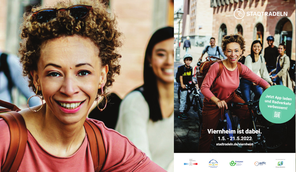 Frau sitzt lachend auf Fahrrad, daneben Plakat mit Schriftzug Stadtradeln