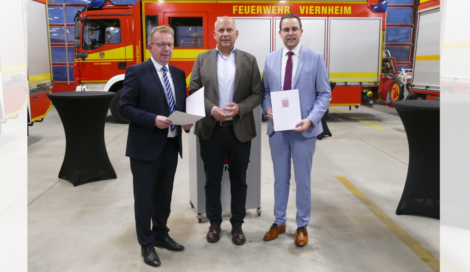 Innenminister Roman Poseck (Bildmitte) übergibt die Förderbescheide an Bürgermeister Matthias Baaß (links) und Ersten Stadtrat Jörg Scheidel.