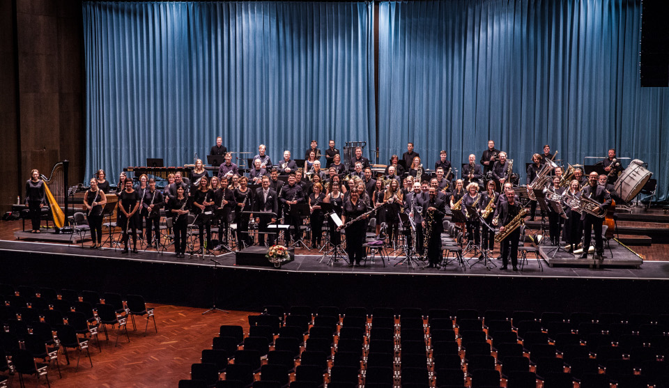 Orchesterspieler stehen mit ihren Instrumenten auf einer Bühne