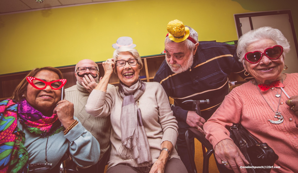 Senioren lachen und tragen lustige Hüte und Brillen
