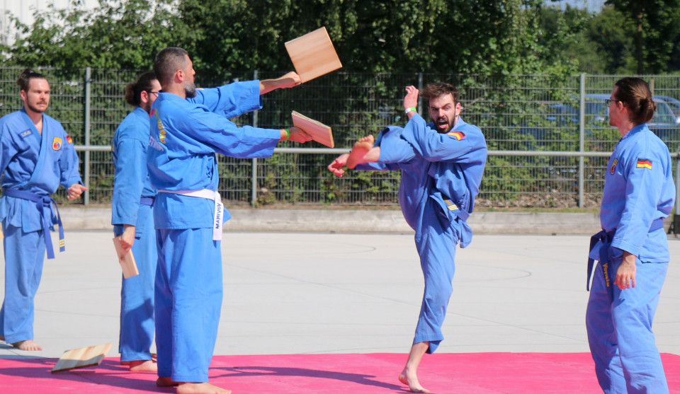 Fünf Kampfsportler in blauen Kampfsportanzügen beim Training
