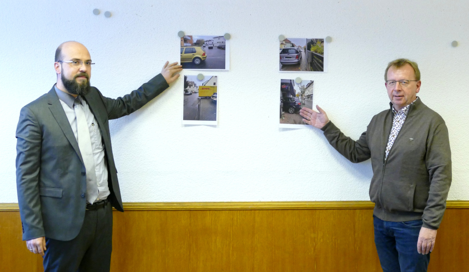 Herr Geschwind und Herr Baaß vor einer Wand mit Fotos zu verschiedenen Verkehrssituationen