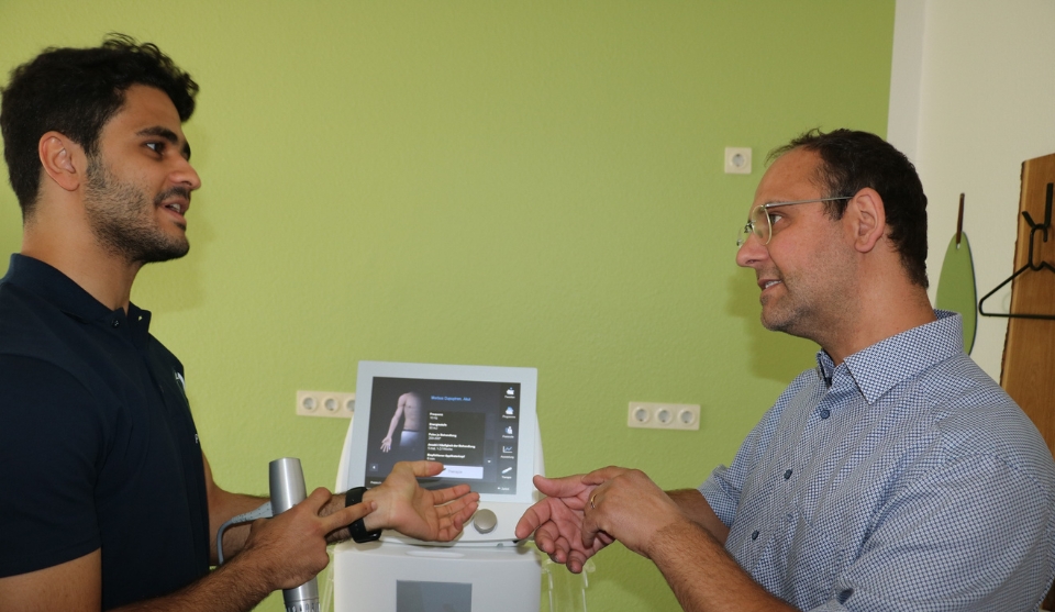 Omar Mohamed (links) erläutert dem städtischen Wirtschaftsförderer Alexander Schwarz die Funktionsweise des Stoßwellengeräts.