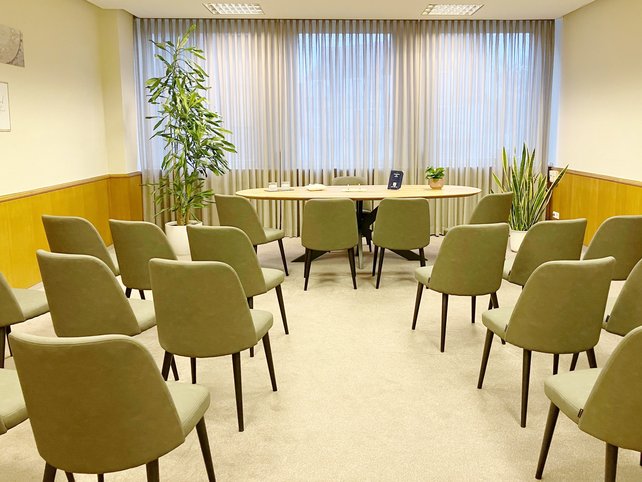 Zimmer mit Stuhlreihen recht und links, Mitte ein Tisch mit vier Stühlen