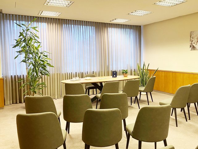 Zimmer mit Stuhlreihen recht und links, Mitte ein Tisch mit vier Stühlen