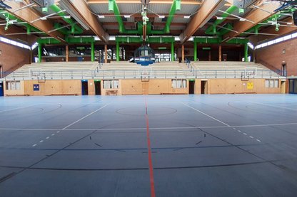 Halle von innen mit blauen Sportbelag und Tribüne