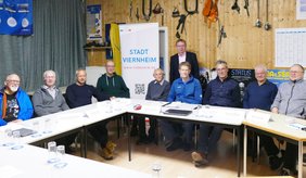 Bürgermeister Matthias Baaß (stehend) stellt das neue Bürgernetzwerk vor, das Interessierten mit Rat und Tat zur Seite steht. ©Stadt Viernheim Personen sitzen um einen Tisch