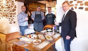 Bürgermeister Matthias Baaß (rechts) und Wirtschaftsförderer Alexander Schwarz (links) mit dem Team und einem Tisch mit einigen Leckereien.