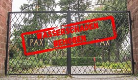 Ein geschlossenes, schwarzes, schmiedeeisernes Eingangstor eines Friedhofs zwischen zwei Sandsteinmauern. Auf beiden Torflügeln befindet sich jeweils eine schwarze Tafel mit der goldfarbenen Aufschrift „PAX“. Hinter dem Tor sind ein Weg, grüne Sträucher und hohe Bäume zu sehen. Quer über das Tor ist ein großer, leicht schräg stehender roter Stempel mit der Aufschrift „WASSERSCHADEN BEHOBEN“ eingeblendet.