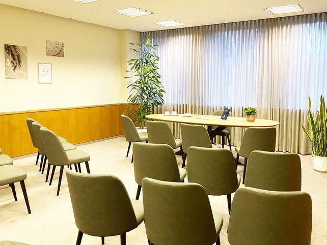 Zimmer mit Stuhlreihen recht und links, Mitte ein Tisch mit vier Stühlen