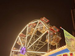 Crepestand und im Hintergrund ein Riesenrad bei Nacht mit bunten Lichtern