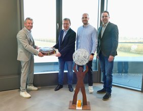 Architekt Roland Träger (links) übergibt gemeinsam mit Pascal Hoffmann (2. v.r.) eine Ellipsen-Torte an die Rathausspitze.