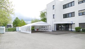 Die Notunterkunft in der Lilienthalstraße ©Stadt Viernheim Gebäude mit Zelt davor und Zimmer mit Stockbetten