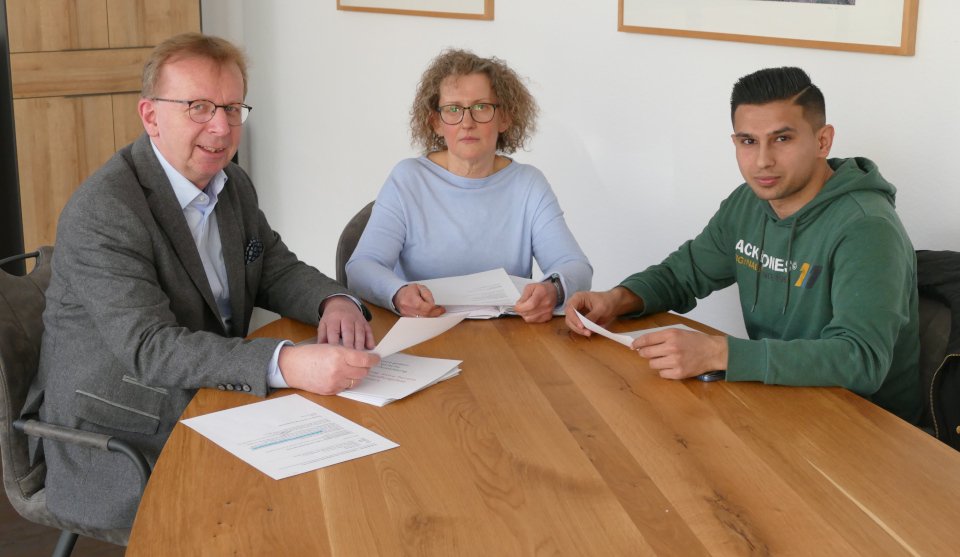 Drei Personen sitzen am Tisch