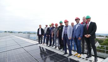 Viele Menschen auf einem Firmendach mit einer erste Photovoltaik-Anlage.  