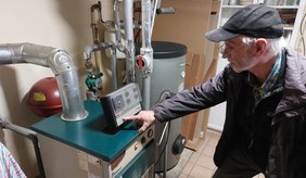 Dipl. Ing. (FH) Karl Rösch bei der Einstellung der Heizkurve ©Stadt ViernheimDipl. Ing. (FH) Karl Rösch bei der Einstellung der Heizkurve ©Stadt Viernheim Karl Rösch, grauhaarig mit Mütze, steht am Heizkessel und drückt auf eine Taste