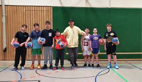 Basketballtrainer René Ringhof (Mitte) freut sich mit Teilnehmenden der offenen Basketball-AG der Jugendförderung für das Basketball-Event.