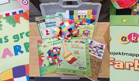 Mit dem Erzählkoffer "Elmar und die Farben" lernen Kinder mit dem kunterbunten Elefant Elmar die Farben kennen. ©Stadt Viernheim Verschiedene Spiele und Bücher auf einem Tisch
