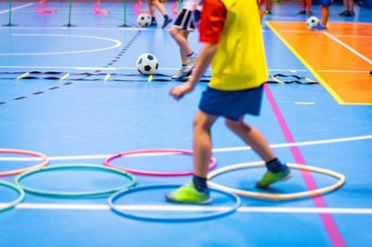 Kind turnt auf blauem Hallenboden mit Ringen